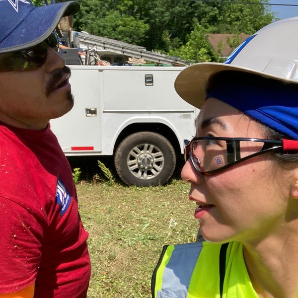 A man talks to a woman in a hardhat.