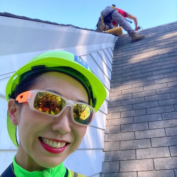 Man and woman on a steep roof replacing shingles.