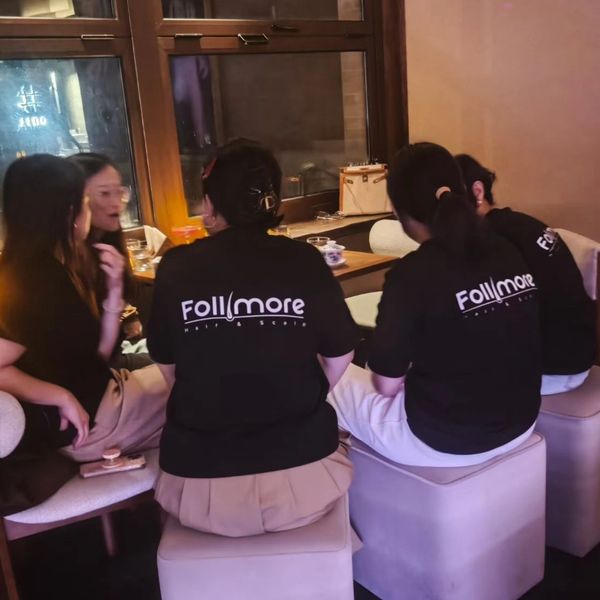 Group wearing matching 'Follmore' shirts seated inside a cozy cafe.