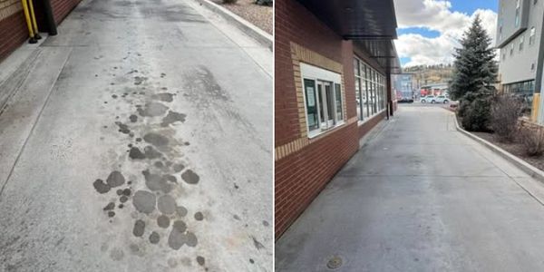 Two concrete driveways, one stained and one clean beside a brick building.