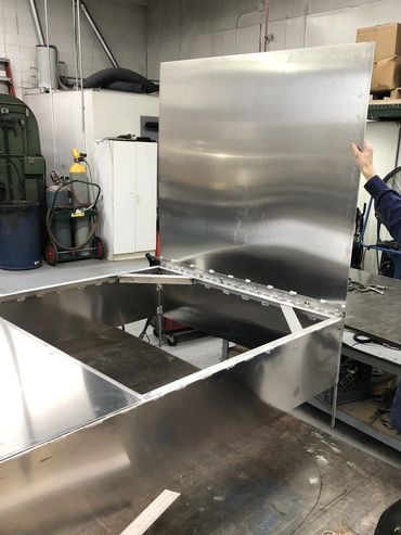 Person lifting a large hinged metal panel.