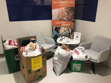 2 cardboard boxes filled with plastic bags in the office of a business called 1891 Financial Life