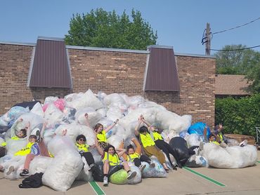 A group of volunteers in safety vests all having jumped into an enormous pile of plastic bags