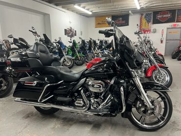 Black touring motorcycle parked indoors among other bikes.