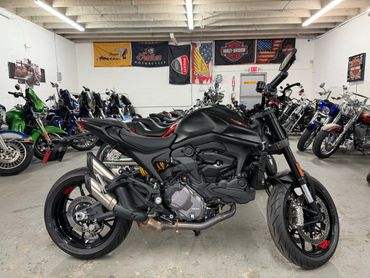 Sleek black motorcycle displayed in a showroom filled with various bikes.