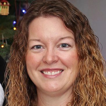 Smiling woman with curly hair and blue eyes.
