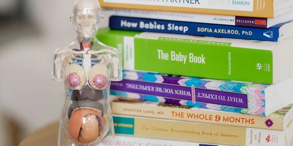 Anatomical pregnancy model with a stack of pregnancy and childbirth books.