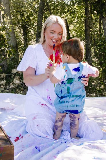 Woman and child playing with paint outdoors.