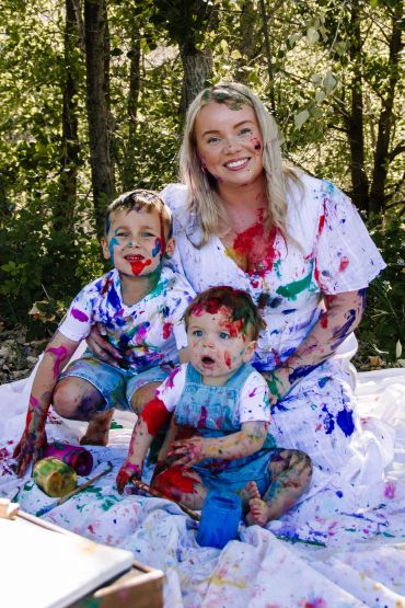 Family covered in colorful paint during outdoor fun.
