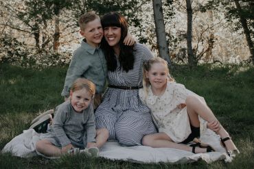 Woman and three children posing on a blanket outdoors.
