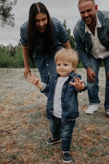 A toddler takes steps toward the camera with parents cheering.