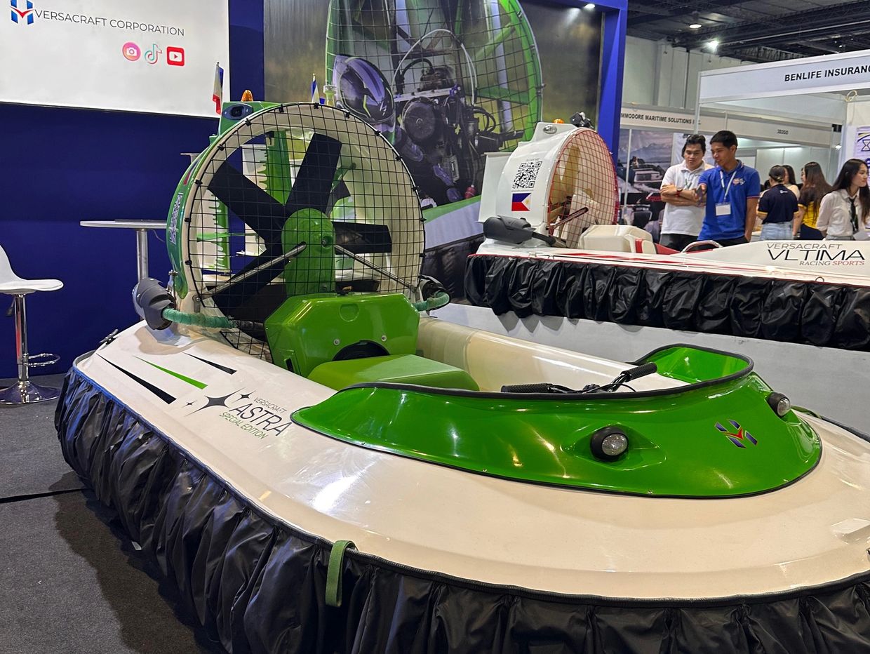 Two hovercrafts displayed indoors with green and white colors and large rear fans.