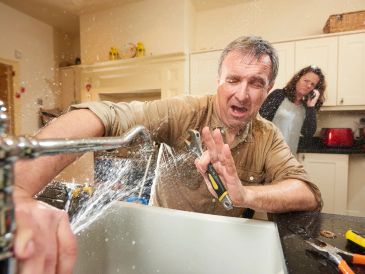 Man struggling to fix a bursting kitchen faucet.
