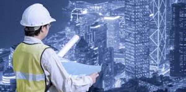 Engineer reviews blueprints overlooking a cityscape at night.