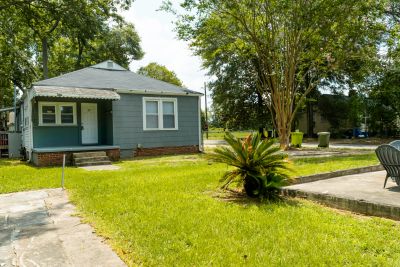 Small blue house with green lawn and patio area.