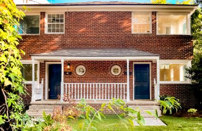 Two-story brick house with a blue double door and white porch.