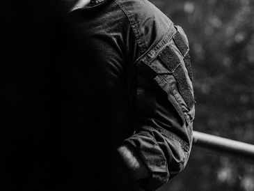 Black and white photo of a person wearing a jacket with patches on the sleeve.