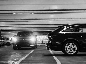 Black and white photo of cars parked in an indoor parking garage.