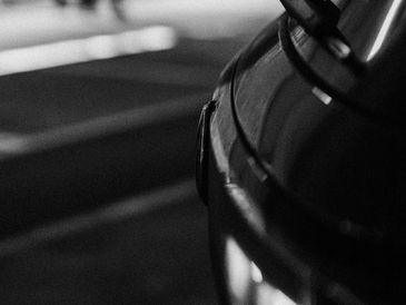 Close-up of a car headlight and front grille in black and white.