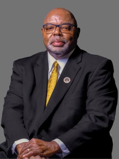 Man in black suit with yellow tie posing.