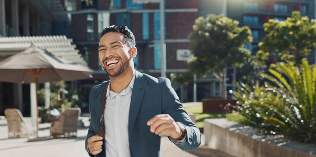 Smiling man in front of buildings with plants around
