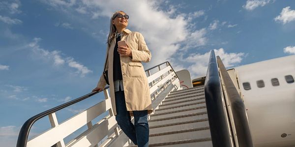 Woman smiling coming down steps off an aeroplane