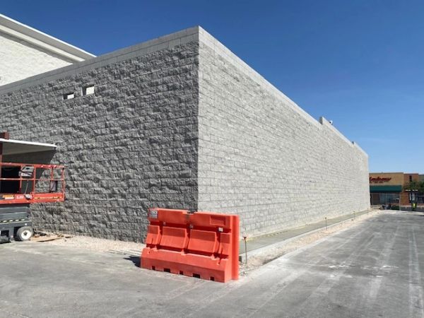 Newly constructed gray brick building with a clear blue sky.