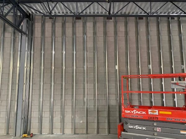 Interior construction with metal studs and a red Skyjack lift.