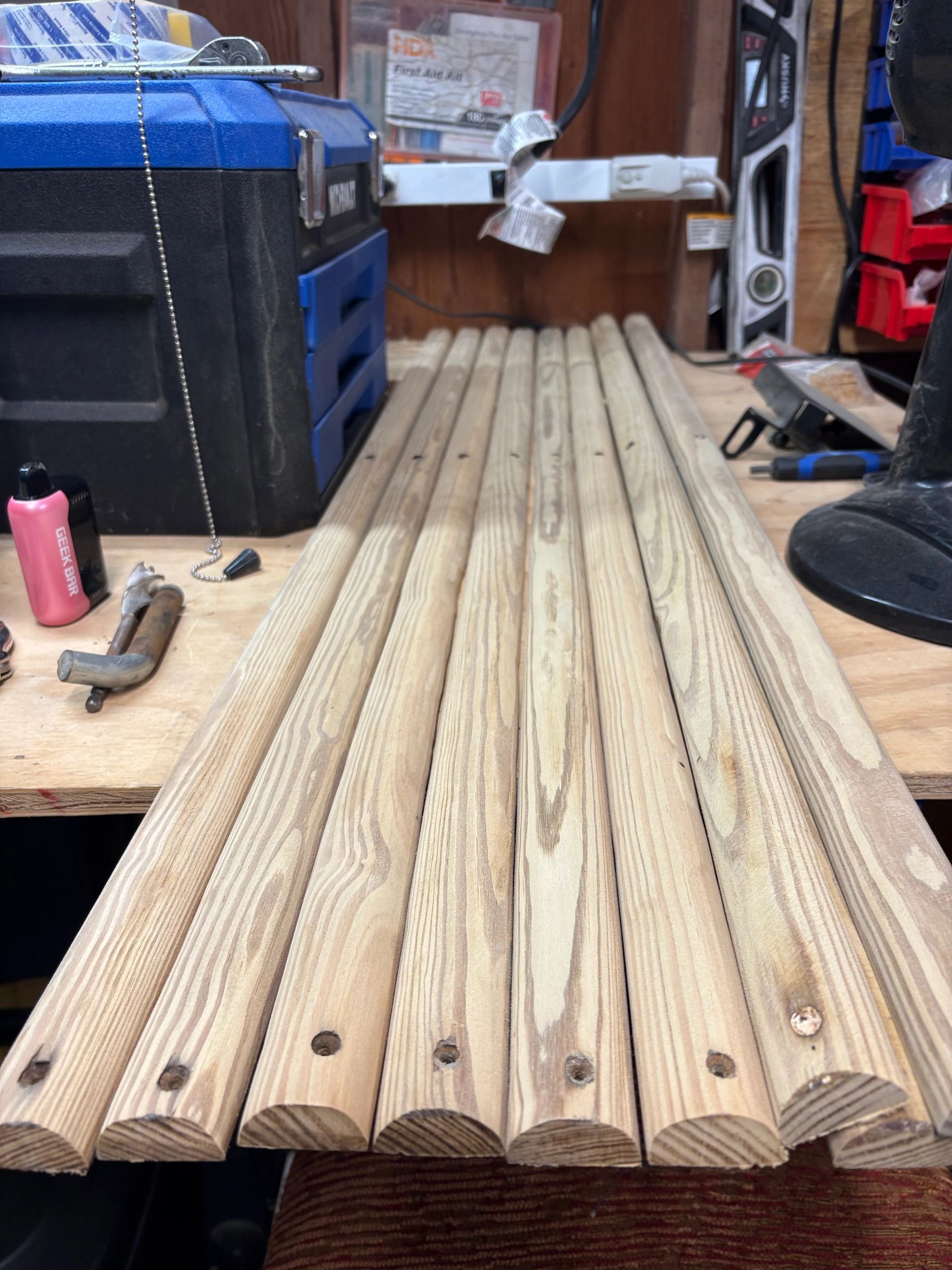 Seven rounded wooden dowels lined up on a workbench.