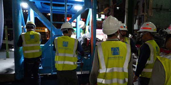 Construction workers in safety vests and helmets working at night.