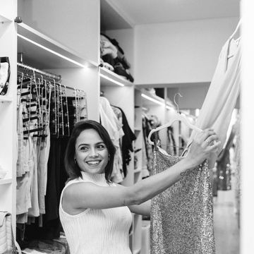 Woman holds a sparkly dress in a closet.