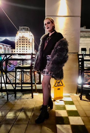 Person with goth style posing on a rooftop at night.
