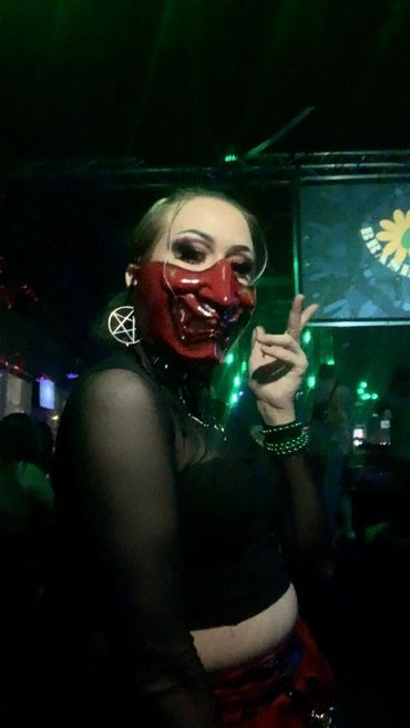 Person wearing a red mask and dark clothing at a party.