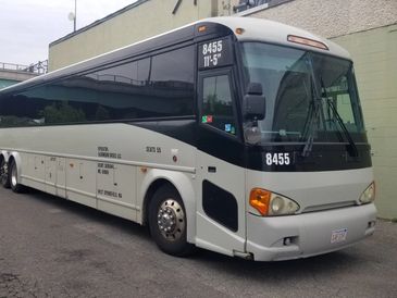 White tour bus parked beside a building.