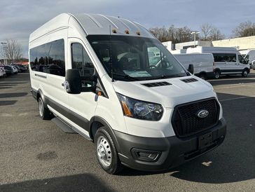 White Ford Transit passenger van parked outdoors on a sunny day.