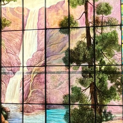 Stained glass window depicting a waterfall and pine tree.