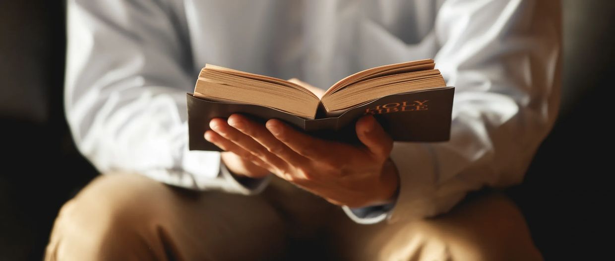 Person holding an open Holy Bible.