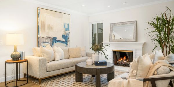 Cozy living room with beige sofas, a round coffee table, and a lit fireplace.