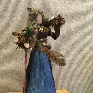 Handcrafted figure made from natural materials with a staff and detailed decorations.