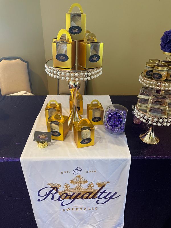 Gold boxes on a pearl-adorned stand at a Royalty Sweetz display.