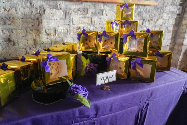 Vegan cookies in gold boxes with purple bows on a purple tablecloth.