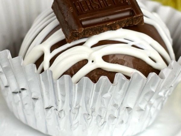 Chocolate truffle with white drizzle and a Hershey's chocolate square on top.