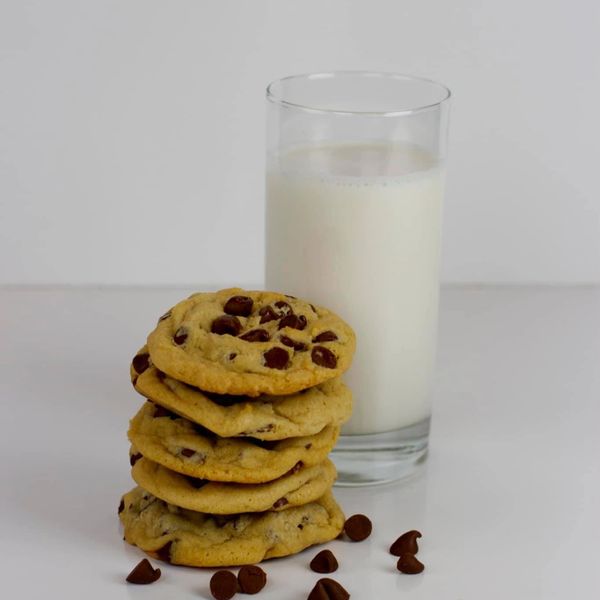 Stack of chocolate chip cookies beside a glass of milk.