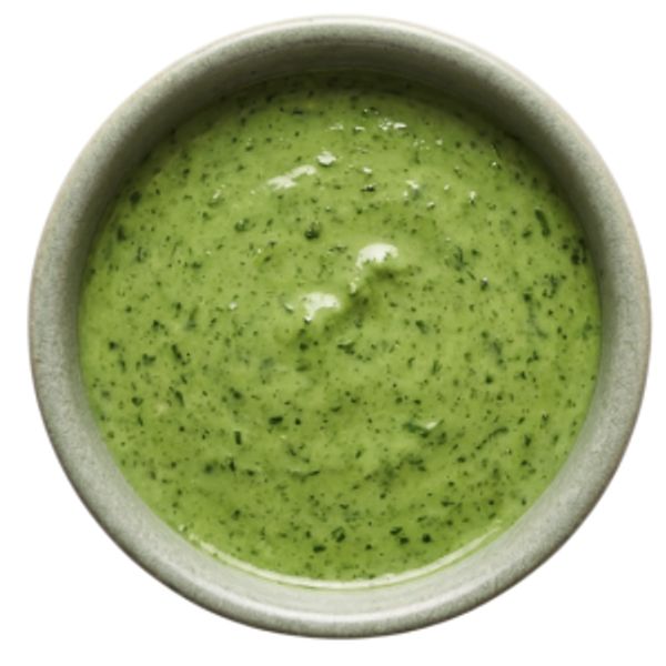 A bowl of creamy green herb sauce with flecks of herbs.