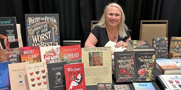 Author Bianca M. Schwarz at a book signing with her works displayed.