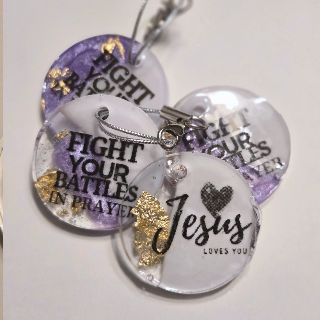 Round keychains with religious messages and decorative gold accents.