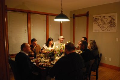 A group of people enjoying a cozy dinner around a table with warm lighting.