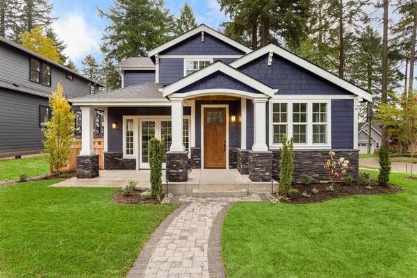 A charming blue house with white trim and a stone pathway.