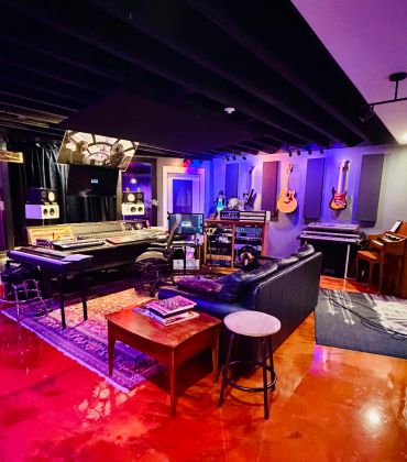 Vibrant music studio with guitars, keyboards, and mixing equipment.