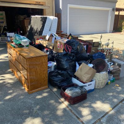 all sorts of miscellaneous household trash and junk in driveway including mattress and dresser 